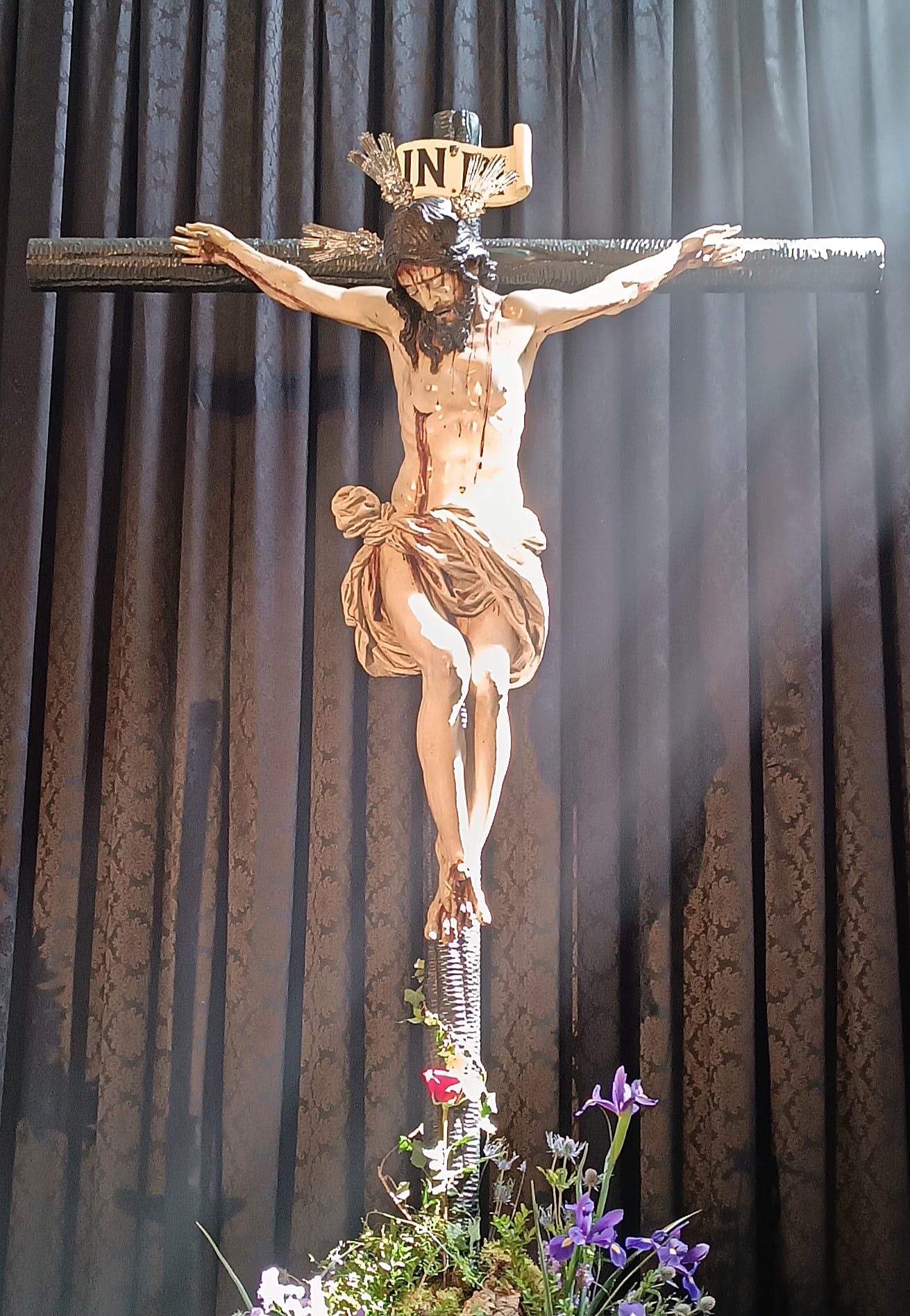 Santísimo Cristo de la Misericordia iluminado ante un cortinaje oscuro