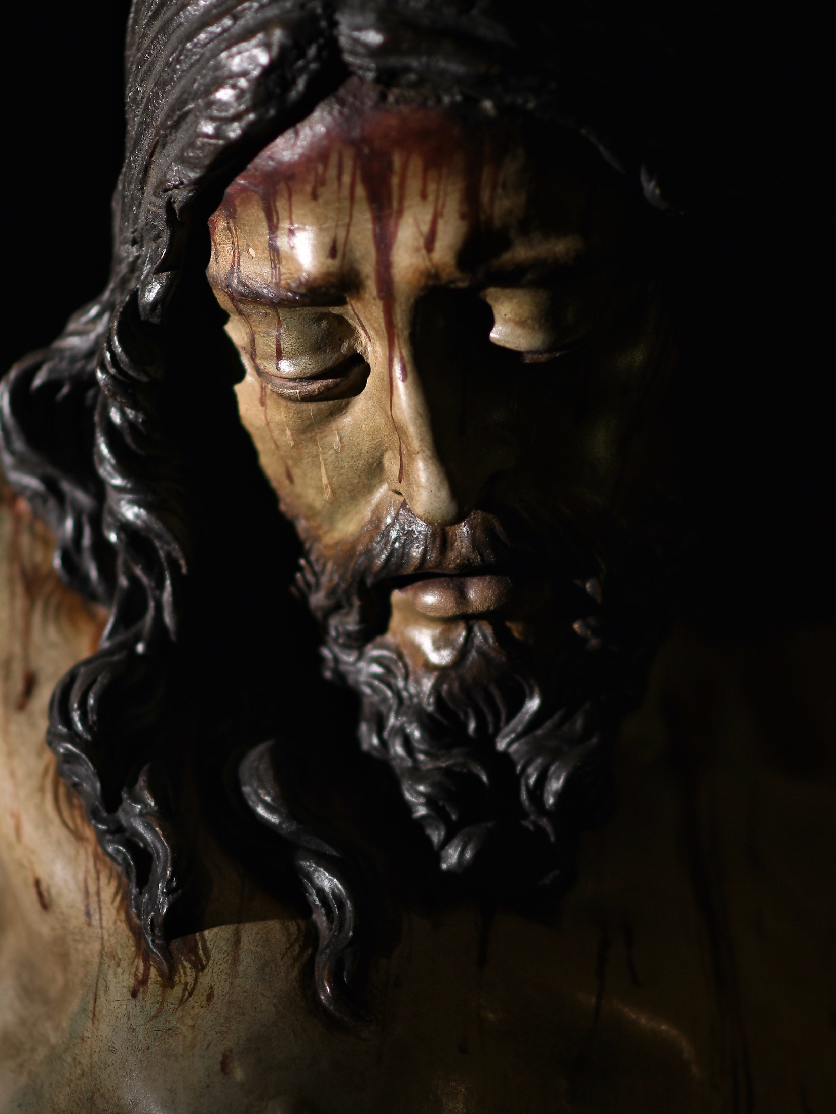 Detalle del rostro del Santísimo Cristo de la Misericordia en penumbra